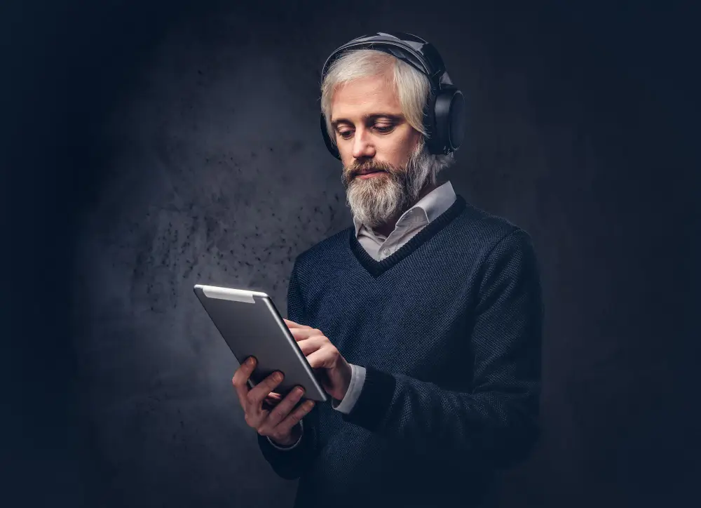 Older man wearing headphones using tablet device